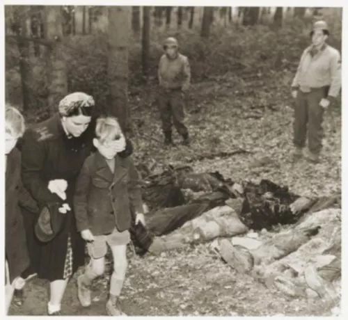 Una madre nel Sauerland passa con il figlio vicino a una fossa comune con i corpi di 57 operaie e operai coatti russi uccisi, scoperta il 3 maggio 1945 vicino a Suttrop. (United States Holocaust Memorial Museum, courtesy of National Archives and Records Administration, College Park).